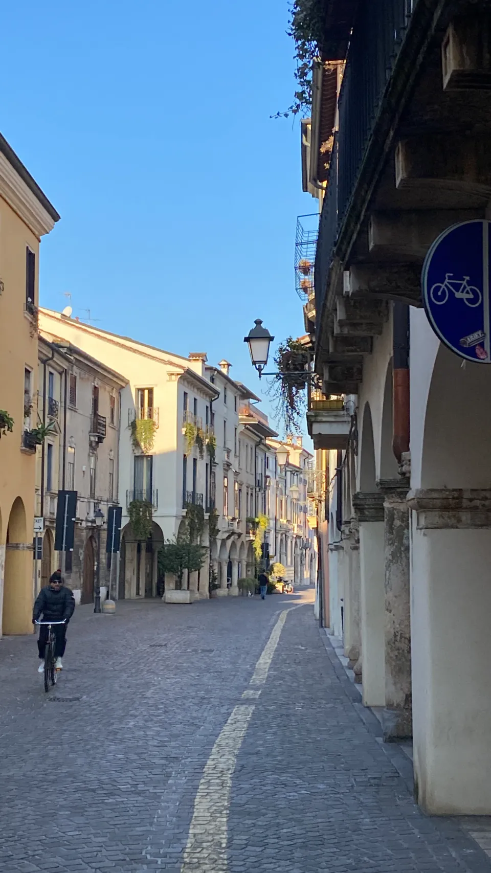 Cyclist riding along an arcaded street in a Veneto historic centre