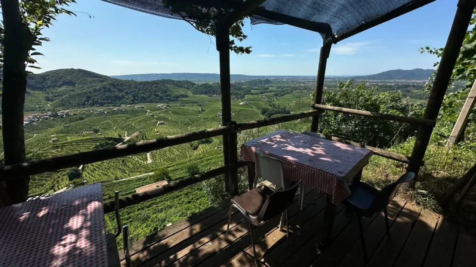 Rustic table under a pergola overlooking the Prosecco vineyards